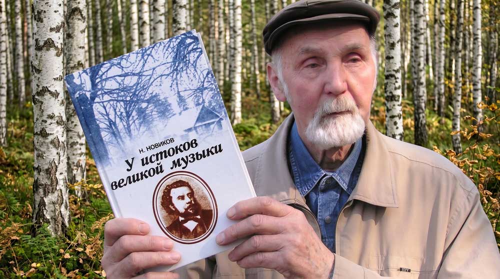 Николай Степанович Новиков с авторским изданием своей книги «У истоков великой музыки». Цифровая художественная реконструкция выполнена на основе прижизненного архивного фотопортрета из фондов «Централизованной библиотечной системы» города Пскова. Образ воссоздан в стилистике художественного портрета на открытом воздухе на фоне псковских березовых просторов, символизирующих неразрывную связь краеведческих изысканий автора с родной землей. Компьютерная обработка, дизайн, проработка библиографических элементов и пейзажная композиция — А. В. Камянчук.