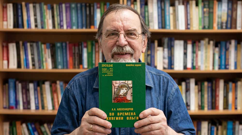 Анатолий Алексеевич Александров с авторским изданием своей историко-краеведческой книги «Во времена княгини Ольги» в читальном зале библиотеки. Цифровая художественная реконструкция выполнена на основе прижизненного архивного фотопортрета из фондов «Централизованной библиотечной системы» города Пскова. Образ воссоздан в стилистике классической интерьерной фотографии начала XXI века с детальным воспроизведением оригинального библиографического оформления юбилейного издания автора, включая изумрудно-зеленую обложку, золотое начертание шрифтов и центральную историческую иллюстрацию. Компьютерная обработка, дизайн, проработка элементов обложки и пространственная композиция — А. В. Камянчук. Анатолий Алексеевич Александров с авторским изданием своей историко-краеведческой книги «Во времена княгини Ольги» в читальном зале библиотеки. Цифровая художественная реконструкция выполнена на основе прижизненного архивного фотопортрета из фондов «Централизованной библиотечной системы» города Пскова. Образ воссоздан в стилистике классической интерьерной фотографии начала XXI века с детальным воспроизведением оригинального библиографического оформления юбилейного издания автора, включая изумрудно-зеленую обложку, золотое начертание шрифтов и центральную историческую иллюстрацию. Компьютерная обработка, дизайн, проработка элементов обложки и пространственная композиция — А. В. Камянчук.
