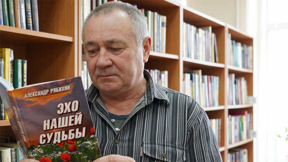 Александр Алексеевич Рябихин с авторским изданием своего поэтического сборника «Эхо нашей судьбы» в интерьере библиотеки. Цифровая художественная реконструкция выполнена на основе прижизненного архивного фотопортрета из историко-краеведческих фондов города Великие Луки. Образ воссоздан в стилистике классической интерьерной фотографии начала XXI века с детальным воспроизведением оригинального библиографического оформления книги автора, включая пейзажную обложку с цветущими маками на переднем плане и оригинальные шрифтовые начертания названия. Компьютерная обработка, дизайн, проработка элементов обложки и пространственная композиция — А. В. Камянчук.